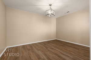 Spare room with dark hardwood / wood-style flooring, a chandelier, and a textured ceiling