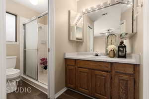 Bathroom with vanity, hardwood / wood-style floors, an enclosed shower, and toilet