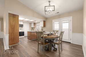 Dining area featuring lofted ceiling, dark wood-type flooring, a notable chandelier, and french doors