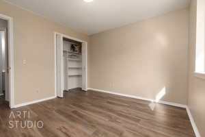 Unfurnished bedroom featuring dark hardwood / wood-style flooring and a closet