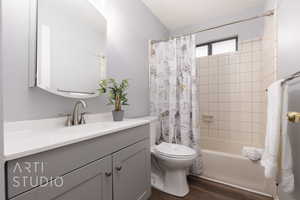 Full bathroom with vanity, hardwood / wood-style floors, shower / bath combination with curtain, and toilet