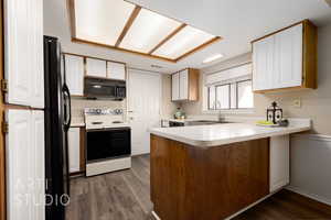 Kitchen featuring white cabinetry, kitchen peninsula, sink, and black appliances