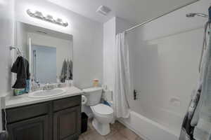 Full bathroom featuring tile patterned flooring, vanity, shower / bath combination with curtain, and toilet