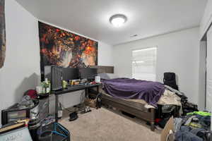 Bedroom with light carpet and a textured ceiling