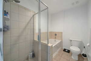 Bathroom featuring tile patterned floors, toilet, and separate shower and tub