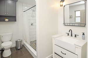 Bathroom with toilet, vanity, tile patterned floors, and a shower with shower curtain