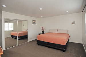 Bedroom featuring dark colored carpet, a textured ceiling, and a closet