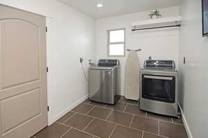 Clothes washing area featuring dark tile patterned flooring and washer and dryer