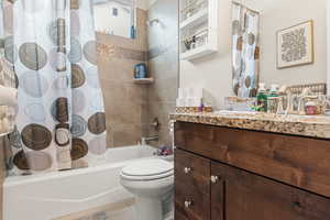 Full bathroom featuring toilet, tile patterned floors, shower / bathtub combination with curtain, and vanity