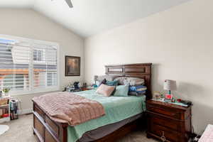 Bedroom with vaulted ceiling, light colored carpet, and ceiling fan