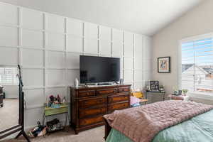 Bedroom with vaulted ceiling, and light colored carpet