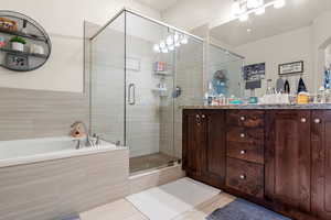 Bathroom featuring tile patterned flooring, vanity, and plus walk in shower