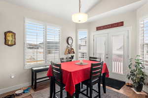 Dining area featuring vaulted ceiling, plenty of natural light, wood-style floors, and french doors