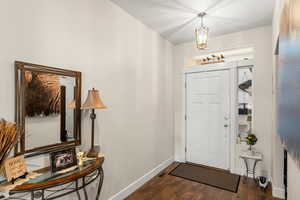 Foyer featuring an inviting chandelier and dark hardwood / wood-style flooring