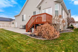 Back of house with a wooden deck, a yard, and a patio area