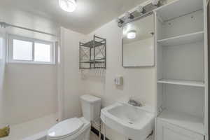 Bathroom featuring walk in shower, toilet, and sink