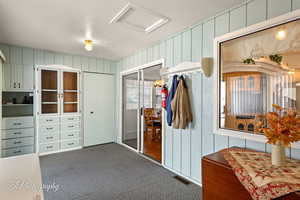 Mudroom featuring a textured ceiling and dark carpet