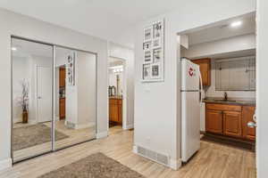 Kitchen featuring dark stone countertops, light wood-type flooring, sink, and refrigerator