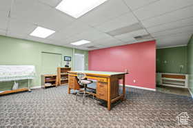 Office space with dark colored carpet and a drop ceiling