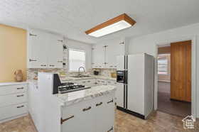 Kitchen with white cabinetry, sink, backsplash, white fridge with ice dispenser, and a textured ceiling