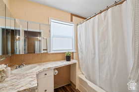 Bathroom with vanity, decorative backsplash, wood-type flooring, and shower / bath combo with shower curtain