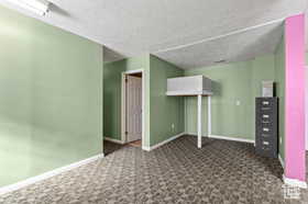 Unfurnished bedroom with a textured ceiling and dark colored carpet