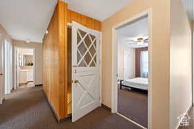 Hall with dark colored carpet and wood walls