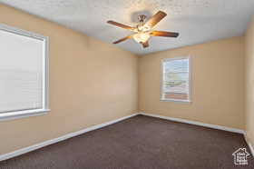 Unfurnished room with ceiling fan, a textured ceiling, and dark colored carpet