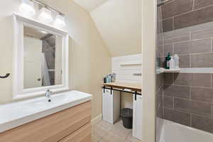 Bathroom featuring tile patterned flooring, tiled shower / bath, and vanity