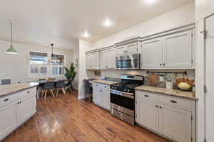 Kitchen featuring decorative light fixtures, light stone countertops, dark hardwood / wood-style floors, and appliances with stainless steel finishes