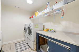 Washroom featuring light tile patterned flooring and washing machine and clothes dryer