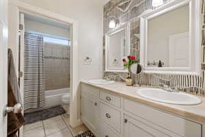 Full bathroom featuring toilet, tile patterned floors, shower / bathtub combination with curtain, and vanity