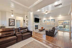 Living room with vaulted ceiling, decorative columns, light hardwood / wood-style floors, and ceiling fan