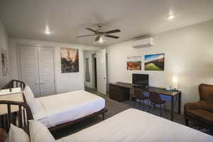 Carpeted bedroom with ceiling fan, a closet, and a wall mounted AC