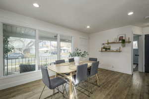 Dining room with dark wood-type flooring and a healthy amount of sunlight