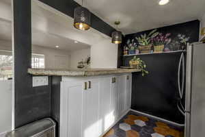 Kitchen with light stone countertops, hanging light fixtures, and white cabinets