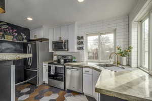 Kitchen with white cabinetry, stainless steel appliances, sink, and tasteful backsplash