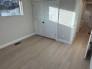 Unfurnished bedroom featuring a closet and light wood-type flooring