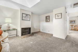 Unfurnished living room featuring a skylight and light carpet