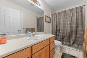 Bathroom with tile patterned flooring, vanity, curtained shower, and toilet