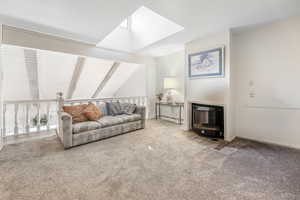 Living room with vaulted ceiling with skylight and carpet floors