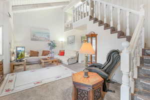 Carpeted living room with high vaulted ceiling and beam ceiling