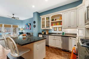 Kitchen with appliances with stainless steel finishes, sink, a kitchen bar, dark stone counters, and a center island