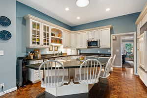 Kitchen featuring sink, a center island, dark parquet flooring, a kitchen bar, and dark stone counters