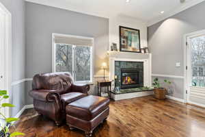 Living area with hardwood / wood-style flooring, a premium fireplace, and ornamental molding