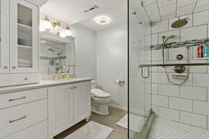 Bathroom with vanity, walk in shower, tile patterned floors, and toilet