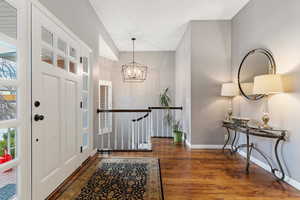 Foyer entrance featuring an inviting chandelier and dark hardwood / wood-style floors