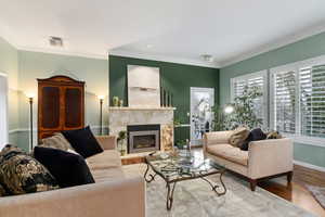 Living room with hardwood / wood-style flooring, ornamental molding, and a high end fireplace