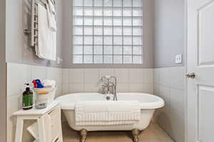 Bathroom featuring tile walls and a bath