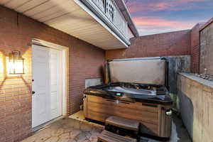 Patio terrace at dusk featuring a hot tub